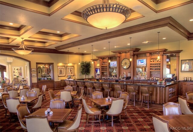 dining area featuring ornamental molding, bar, coffered ceiling, and beam ceiling