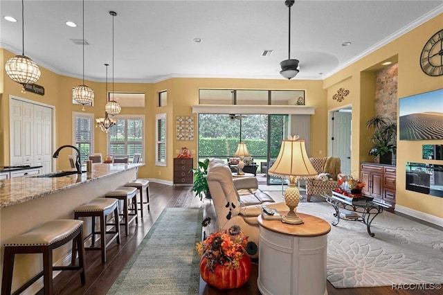 living room featuring sink, an inviting chandelier, dark hardwood / wood-style floors, and ornamental molding