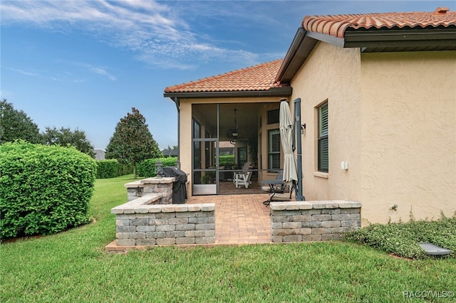 rear view of property with a sunroom, a patio, and a lawn