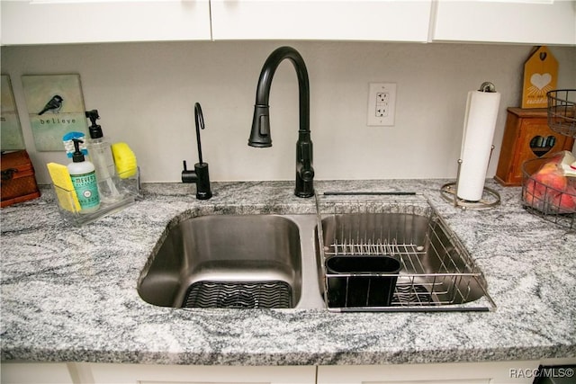 room details with light stone counters, white cabinets, and a sink