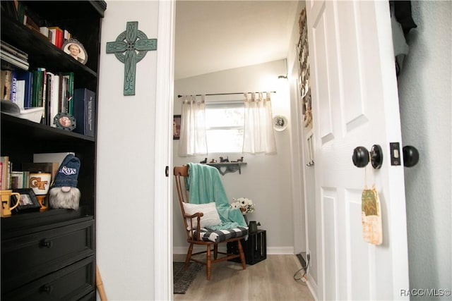 interior space featuring lofted ceiling, light wood-type flooring, and baseboards