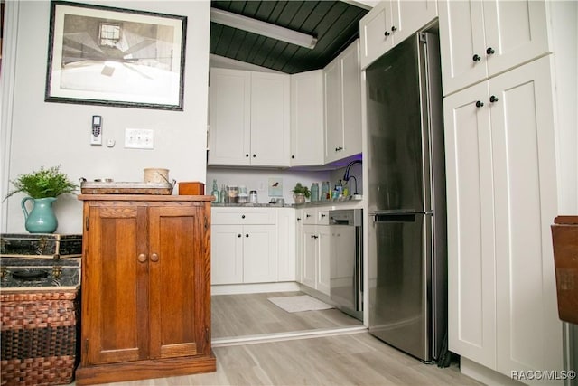 kitchen featuring light countertops, freestanding refrigerator, light wood-type flooring, and white cabinetry