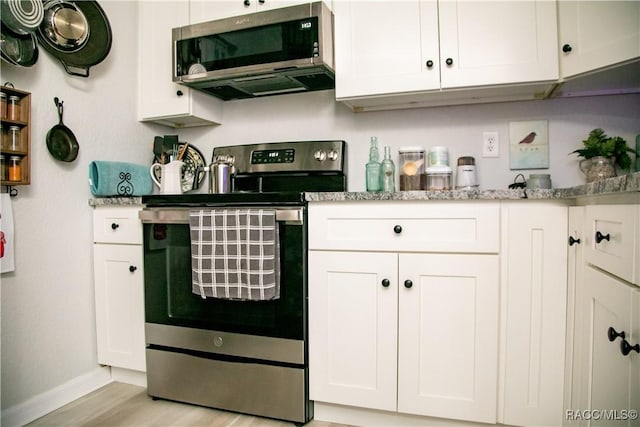 kitchen with baseboards, light wood-style flooring, appliances with stainless steel finishes, light stone counters, and white cabinetry