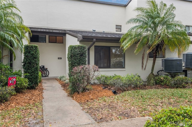 doorway to property featuring stucco siding and central AC unit