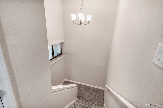 stairway with baseboards, an inviting chandelier, carpet flooring, and a textured wall