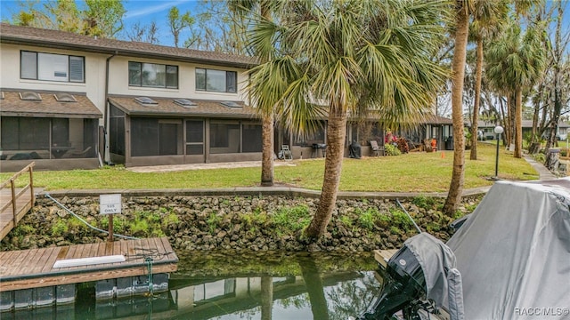 rear view of property featuring a yard, stucco siding, and a sunroom