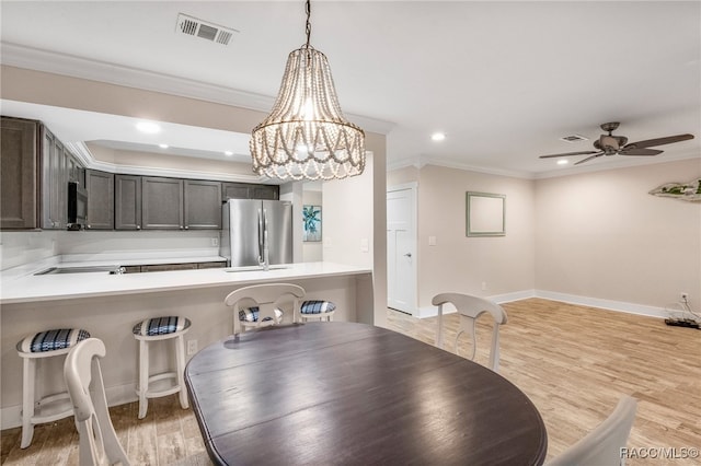 dining room featuring light wood-type flooring, visible vents, and crown molding