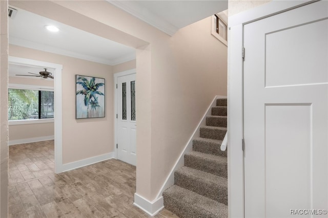 stairs featuring crown molding, wood finished floors, baseboards, and visible vents