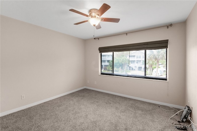 carpeted empty room with a ceiling fan and baseboards