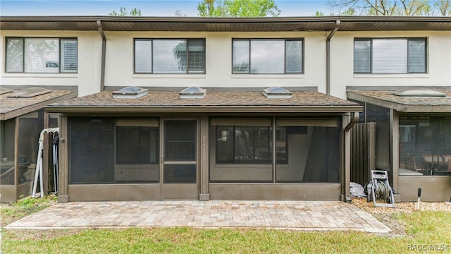 rear view of property featuring stucco siding and a sunroom