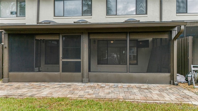 rear view of house with stucco siding and a sunroom