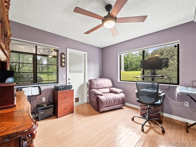 home office with a textured ceiling, light hardwood / wood-style floors, baseboard heating, and ceiling fan