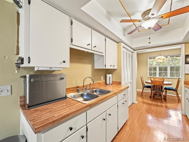 kitchen with white cabinets, light hardwood / wood-style floors, sink, and hanging light fixtures