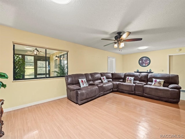 living room featuring ceiling fan, light hardwood / wood-style floors, and a textured ceiling