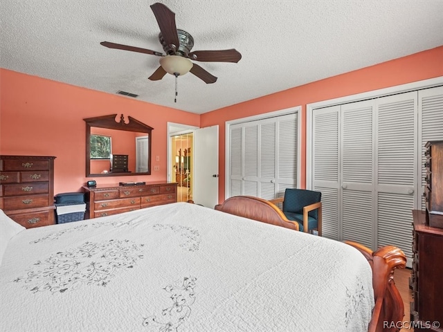 bedroom with ceiling fan, a textured ceiling, and multiple closets