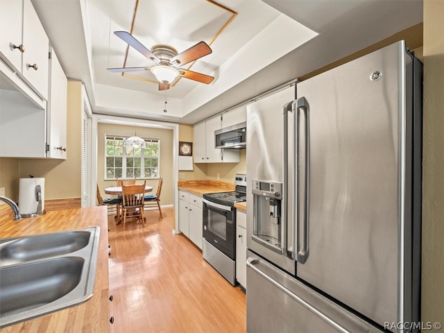 kitchen featuring a tray ceiling, sink, white cabinets, and stainless steel appliances