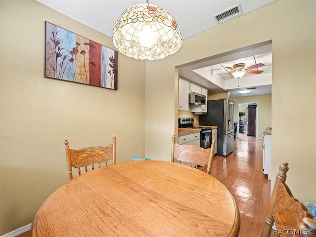 dining room with hardwood / wood-style flooring, ceiling fan, and a tray ceiling