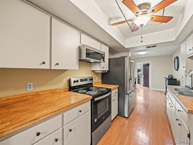 kitchen featuring wood counters, white cabinets, light hardwood / wood-style flooring, ceiling fan, and appliances with stainless steel finishes