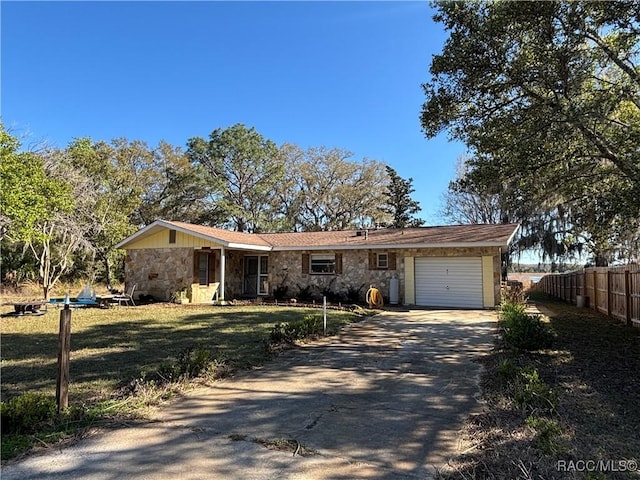 ranch-style house with driveway, stone siding, an attached garage, and fence