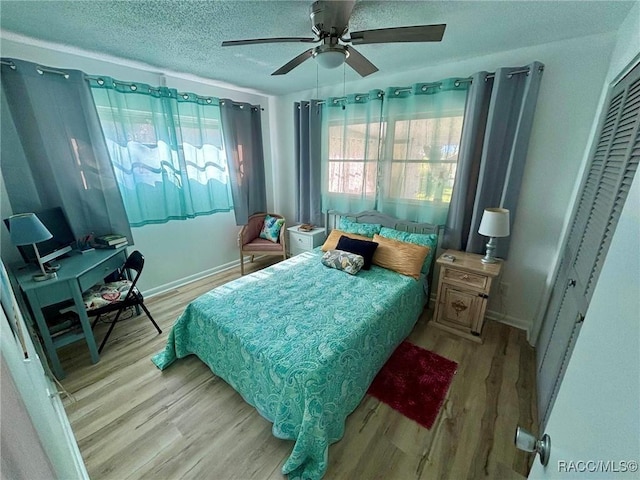 bedroom with light wood-type flooring, ceiling fan, a closet, and a textured ceiling