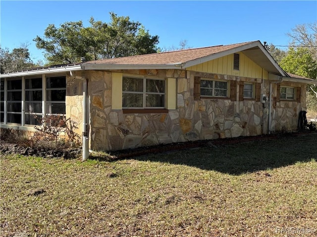 view of home's exterior with stone siding and a yard