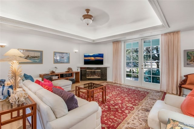 living room with a raised ceiling, ornamental molding, and a fireplace