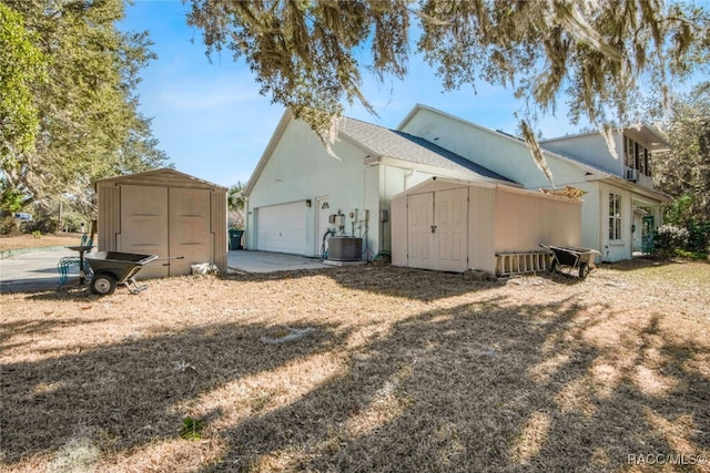 rear view of house featuring central air condition unit and a shed