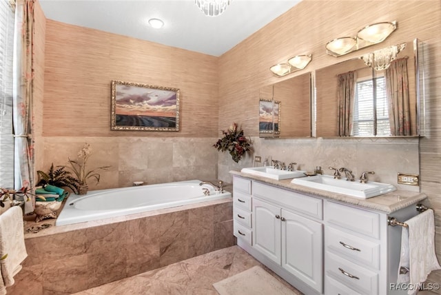 bathroom with tiled tub, vanity, and tile walls