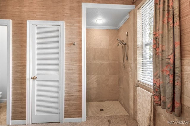 bathroom featuring crown molding and a tile shower