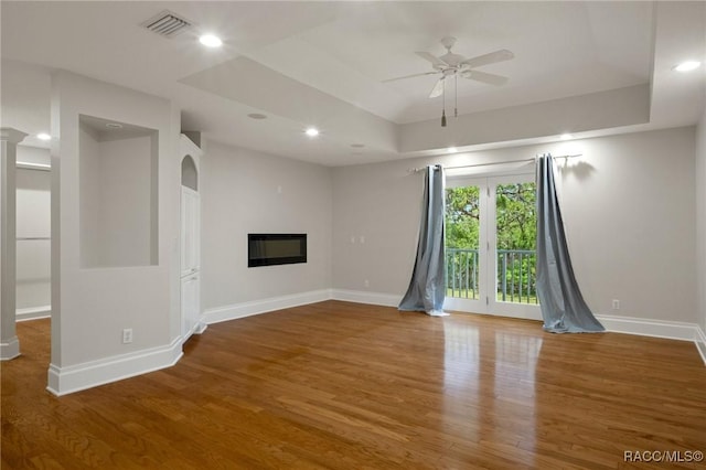 4160 W Bonanza Dr, Beverly Hills, FL 34465 - unfurnished living room with wood finished floors, ceiling fan, baseboards, a glass covered fireplace, and a raised ceiling
