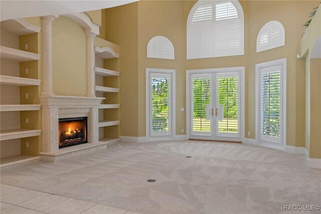 4160 W Bonanza Dr, Beverly Hills, FL 34465 - unfurnished living room featuring carpet floors, a towering ceiling, a high end fireplace, baseboards, and french doors