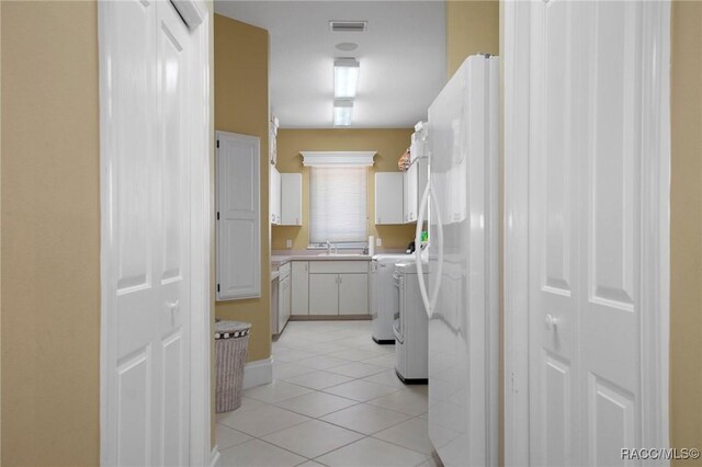 4160 W Bonanza Dr, Beverly Hills, FL 34465 - kitchen featuring light tile patterned floors, light countertops, independent washer and dryer, freestanding refrigerator, and white cabinets