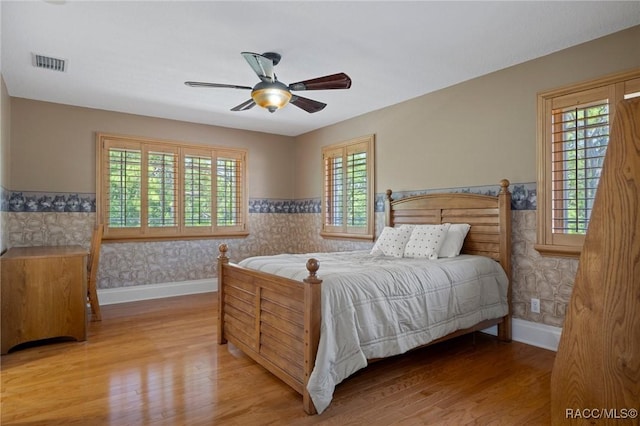 4160 W Bonanza Dr, Beverly Hills, FL 34465 - bedroom with multiple windows, wood finished floors, baseboards, a wainscoted wall, and wallpapered walls