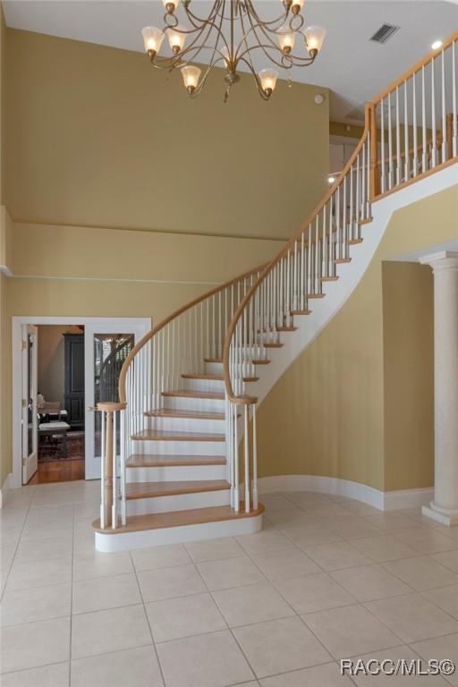 4160 W Bonanza Dr, Beverly Hills, FL 34465 - stairs featuring a high ceiling, tile patterned flooring, a chandelier, decorative columns, and baseboards