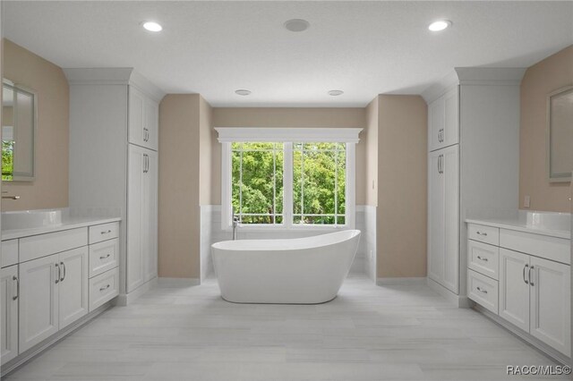 4160 W Bonanza Dr, Beverly Hills, FL 34465 - bathroom featuring two vanities, a freestanding bath, wood finished floors, baseboards, and recessed lighting