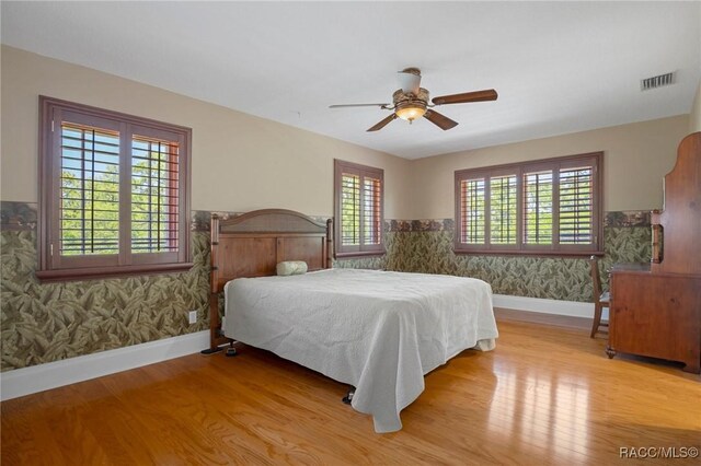 4160 W Bonanza Dr, Beverly Hills, FL 34465 - bedroom featuring wallpapered walls, wood finished floors, baseboards, a ceiling fan, and wainscoting