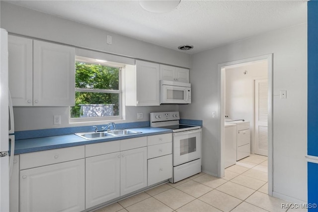 kitchen with white appliances, washer and dryer, a sink, white cabinets, and light tile patterned floors
