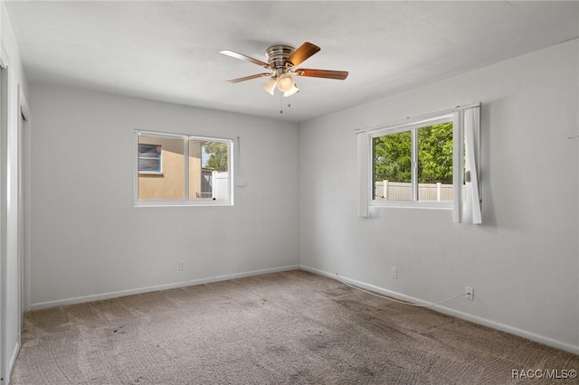 unfurnished room featuring healthy amount of natural light, carpet flooring, a ceiling fan, and baseboards