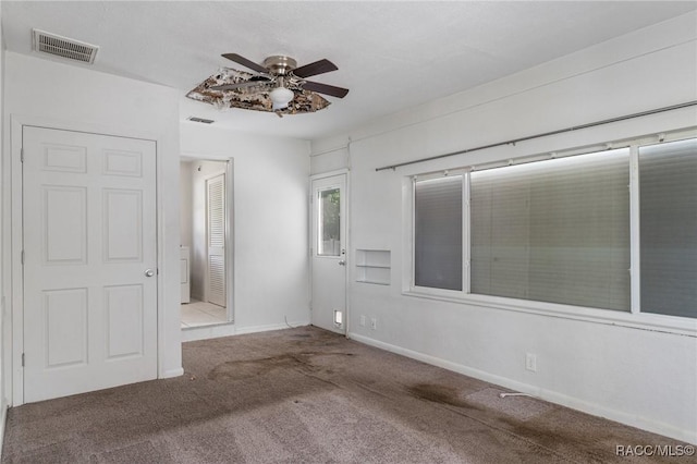 carpeted spare room with a ceiling fan and baseboards