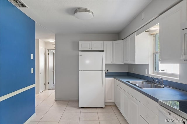 kitchen featuring freestanding refrigerator, white cabinetry, and light tile patterned floors
