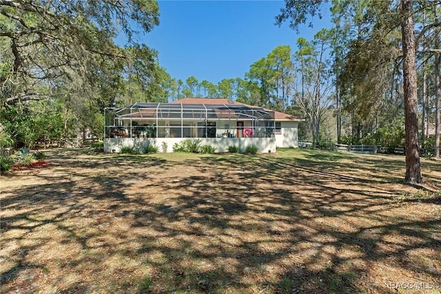 rear view of house featuring a lanai and fence