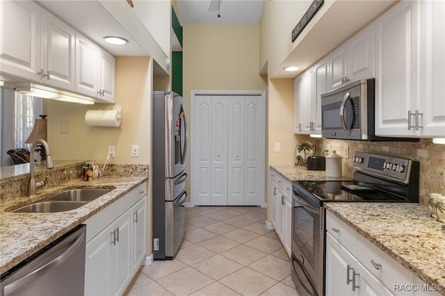 kitchen with stainless steel appliances, white cabinets, a sink, and backsplash