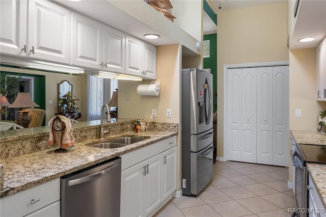 kitchen with light tile patterned floors, stainless steel appliances, white cabinets, a sink, and light stone countertops