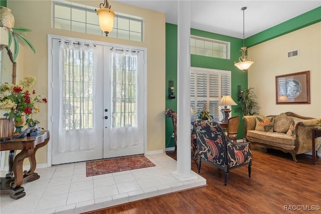 foyer with decorative columns, baseboards, visible vents, wood finished floors, and french doors