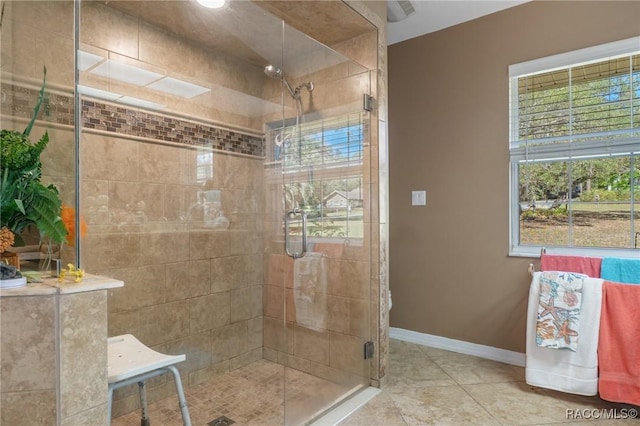 bathroom featuring tile patterned floors, a shower stall, and baseboards