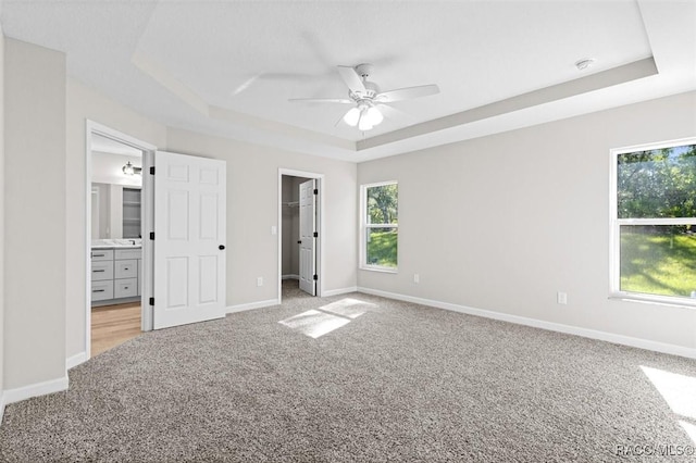 5379 N Nakoma Dr, Beverly Hills, FL 34465 - unfurnished bedroom with a raised ceiling, light carpet, a walk in closet, connected bathroom, and ceiling fan