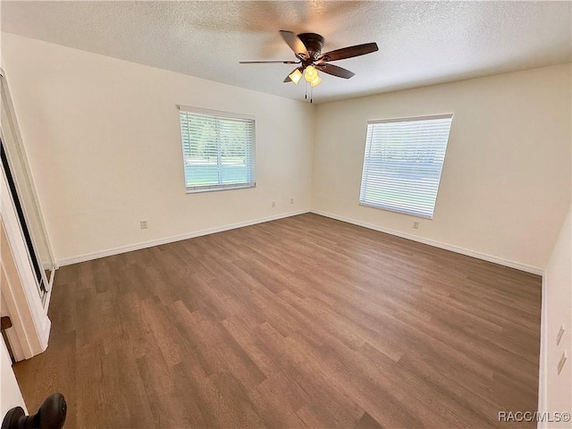 spare room featuring a ceiling fan, a textured ceiling, dark wood-style floors, and baseboards