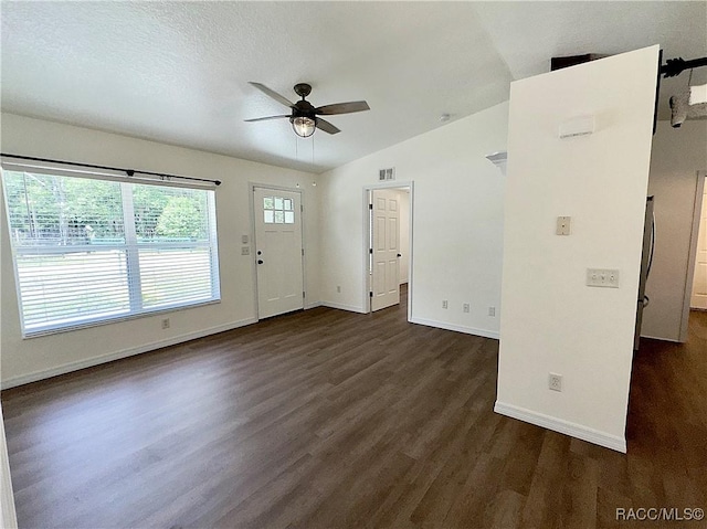 interior space featuring visible vents, lofted ceiling, baseboards, ceiling fan, and dark wood-type flooring