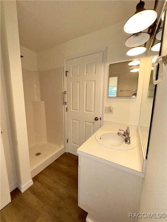 bathroom with vanity, walk in shower, and wood finished floors