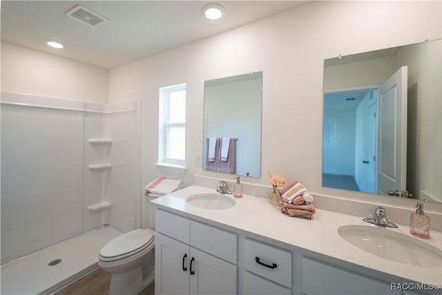 bathroom with a shower, hardwood / wood-style floors, vanity, and toilet